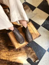 Bota de cuero marrón con suela gruesa y detalles elásticos en los costados.