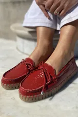 Mocasín náutico dorado de cuero con detalle de lazo en la parte delantera y suela de goma color caramelo.