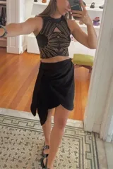 Minifalda negra con corte asimétrico y drapeado lateral.