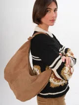 Bolso hobo de cuero color marrón claro, con cierre superior y correa de hombro ajustable.