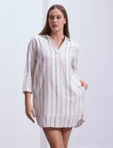 Vestido corto de algodón a rayas verticales en tonos beige, gris y blanco. Tiene cuello solapa, escote en V, mangas 3/4 regulables con presilla y botón, y bolsillos laterales.