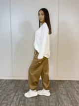 Pantalón babucha cargo color beige, de corte holgado, con cintura elástica, bolsillos laterales y tobillos ajustados.