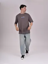 Remera blanca de corte recto con estampado de un auto clásico frente a un skyline urbano.