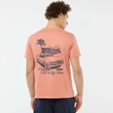 Remera color salmón de manga corta con cuello redondo y estampado pequeño en el pecho con una palmera y texto en azul.