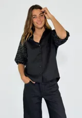 Camisa negra con mangas 3/4 abullonadas con lentejuelas.