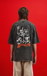 Remera oversize de algodón premium, color gris oscuro con efecto nevado (acid wash), con estampa frontal de calaveras inspiradas en Disney y texto "CHILLED BY BONE".