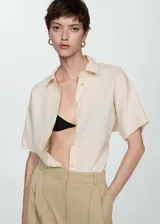 Camisa blanca de lino con cuello clásico, manga corta y cierre frontal con botones.