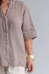 Camisa color visón de lino italiano, con cuello mao, manga corta y cierre frontal con botones.