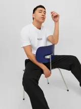 Camiseta blanca de manga corta y cuello redondo con estampado pequeño en el pecho.
