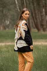 Cárdigan negro de lana con apliques de hojas en tonos beige, naranja y marrón.