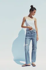 Pantalón de jean celeste de tiro alto, corte mom fit, largo regular y roturas en las rodillas.