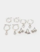 Set de seis pares de aros plateados con diferentes diseños: dos pares de argollas pequeñas lisas, dos pares de argollas con dijes colgantes (cruz y corazón) y dos pares de aros tipo botón (flor y triángulo).