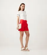 Short de vestir color rojo vibrante, tiro alto, con pliegues delanteros y cinturón ancho con hebilla cuadrada forrada a tono.