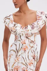 Vestido midi blanco con estampado floral en tonos naranja y marrón. Presenta escote cuadrado con volados, mangas cortas con volados y falda escalonada con volados.