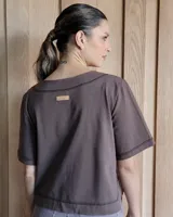 Remera negra con cuello redondo y mangas cortas, con detalle de pespuntes blancos en cuello, mangas, bolsillos frontales y ruedo.