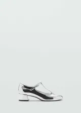 Zapato plateado de charol con tacón bloque metalizado, tira sobre el empeine y punta redonda.