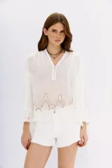 Camisa negra amplia de algodón con escote redondo y abertura corta con botones en el frente. Cuenta con bordados cut-out en el ruedo y mangas largas terminadas en puño con botón.