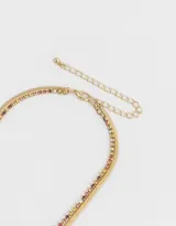 Collar corto con doble cadena dorada de metal, una de ellas con strass de colores. Cierre de mosquetón.