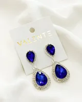 Aros colgantes plateados con dos piedras azules en forma de lágrima, rodeadas de strass.