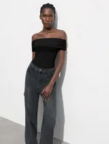 Body negro con escote bote drapeado y broches inferiores.