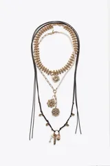 Set de tres collares dorados de diferentes largos. El primero es de eslabones con medalla labrada y perlas. El segundo combina perlas y eslabones con colgantes de medallas labradas. El tercero es de cordón con nudos y charms de diferentes formas.