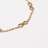 Pulsera dorada de cadena fina con tres dijes de infinito.