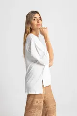 Remerón blanco de algodón, con mangas 3/4 con pliegues y elástico en el puño, y aberturas laterales en el ruedo.