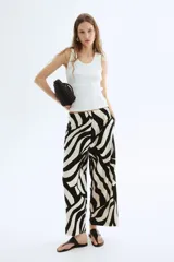 Pantalón tobillero de viscosa con estampado abstracto en blanco y negro, tiro alto con elástico en la cintura, bolsillos laterales y piernas amplias rectas.