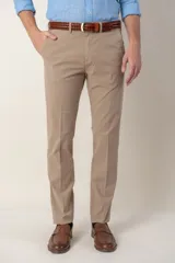 Pantalón de vestir color beige, de corte recto, con bolsillos laterales y traseros. Se ajusta a la cintura con cinturón de cuero marrón.