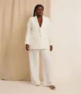 Blazer de poliéster color blanco, de corte sastrero, con cuello solapa, botón dorado redondo contrastante, manga larga con botón y bolsillos fake de solapa delanteros.
