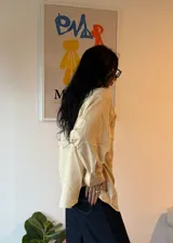 Camisa color crema a rayas verticales finas, de corte oversize y manga larga.