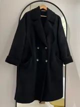 Tapado largo negro de gamuza con interior de corderito. Tiene detalles de corderito visible en cuello y bolsillos, y cierre frontal con botones.