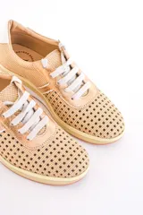 Zapatillas de cuero color dorado con diseño perforado, cordones blancos y suela de goma.