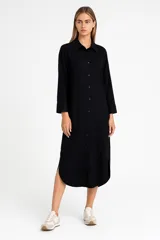 Vestido camisero midi negro de lino, corte recto, con cuello camisero, manga larga y abertura lateral. Cierre frontal con botones.