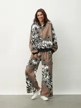 Campera bomber con estampado de flores en blanco y negro sobre fondo beige y marrón. Tiene cuello, puños y bajo acanalados en negro, y cierre frontal con cremallera.