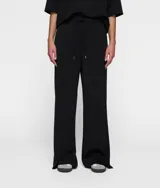Pantalón ancho negro de corte relajado, confeccionado en tejido de buceo activo supersuave. Presenta cintura elástica con cordón, bolsillos laterales, logo de mini rayas estampado bajo el bolsillo izquierdo, pequeñas aberturas en la parte inferior de las piernas y un bolsillo de ribete falso en la parte trasera.