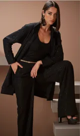 Conjunto de saco y pantalón negro con textura y detalles brillantes. El saco es de corte recto con solapas y bolsillos. El pantalón es de corte palazzo.