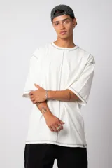 Remera negra oversize con mangas cortas y costuras a la vista en color blanco.