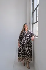 Vestido largo de corte amplio con estampado animal print en tonos negro y beige, cuello camisero y mangas largas.