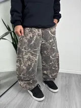 Pantalón baggy de jean con estampado de camuflaje en tonos marrones y beige.