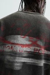 Camiseta negra con efecto lavado, corte boxy fit, cuello redondo y manga corta. Estampado rojo en el frente.