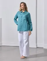 Camisa blanca de lyocell, marca Dash. Tiene cuello con solapa, abertura central con botones, mangas largas regulables con presilla y botón, y dos bolsillos delanteros aplicados.