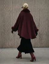 Ruana o poncho negro de tejido suave, con cuello y puños adornados con apliques de piel sintética (faux fur).