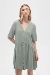 Vestido corto color crema, de corte holgado, con cuello en V y botones frontales.