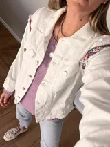 Campera de jean oversize, color rojo desgastado, con aplicaciones de tapicería multicolor de estilo étnico en hombros y ruedo, y terminaciones desflecadas.