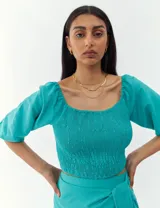 Top turquesa con escote cuadrado, mangas abullonadas y cuerpo fruncido.