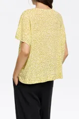 Remera de tejido liviano color amarillo pálido con estampado animal print en tono más oscuro, corte holgado y cuello en V.