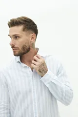 Camisa de manga larga para hombre, color blanco con rayas verticales finas en tonos grises y azules. Confeccionada en una mezcla de lino y algodón, de corte semi slim y logo bordado en el pecho.