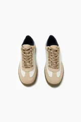 Zapatillas deportivas bajas color beige y blanco, con cordones y suela marrón.
