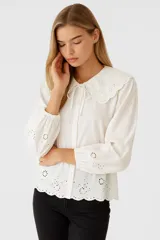 Camisa celeste de algodón con bordados florales, cuello babero con volados y lazo.
